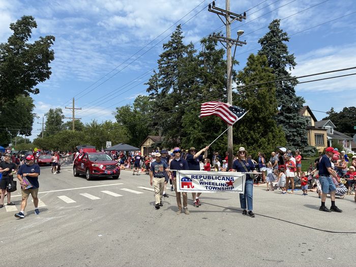 ROWT members marching with the Republicans of Wheeling Township banner and an American flag in the Independence Day parade